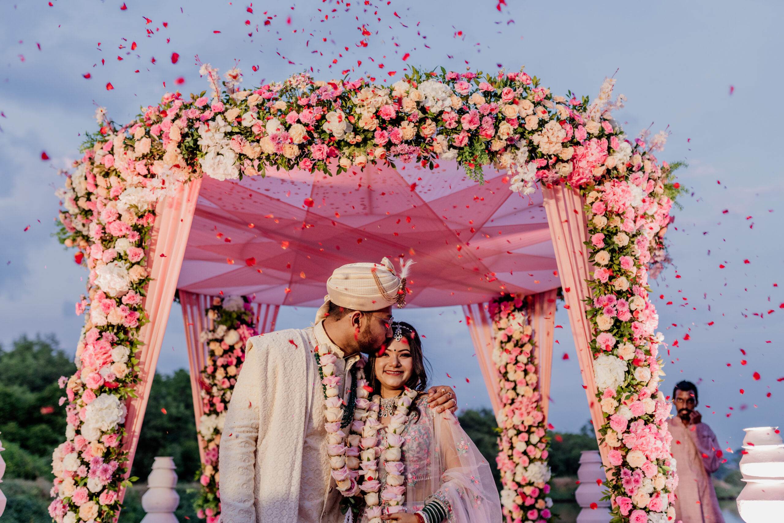 Couple seated on a red and gold floral sofa at a decorated wedding reception